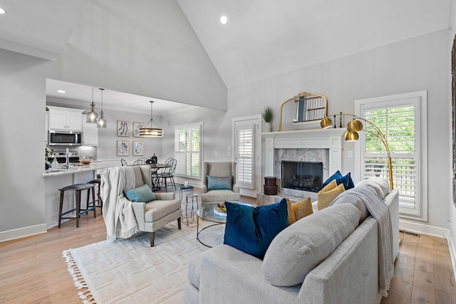 1209 Janie Sue Ct, Lebanon, TN 37087 - living area with high vaulted ceiling, a fireplace, light wood-style floors, plenty of natural light, and ornamental molding