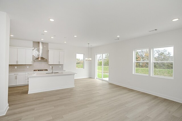 kitchen featuring light countertops, light wood-style flooring, wall chimney exhaust hood, recessed lighting, and backsplash