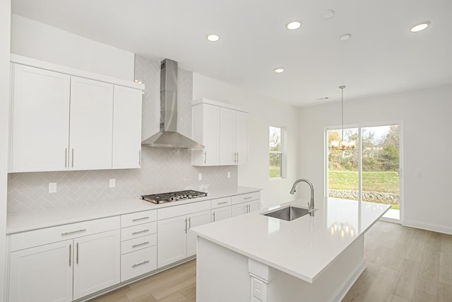 kitchen with decorative backsplash, wall chimney range hood, recessed lighting, a sink, and stainless steel gas stovetop
