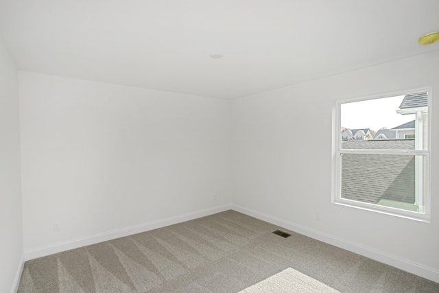 empty room featuring baseboards, light carpet, and visible vents