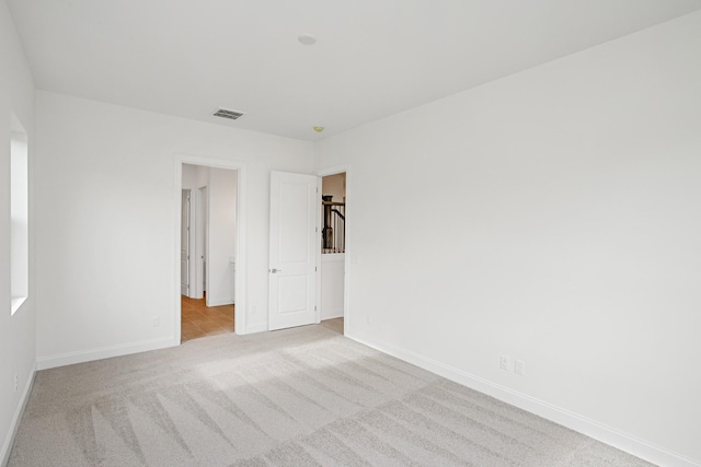 carpeted empty room with visible vents and baseboards