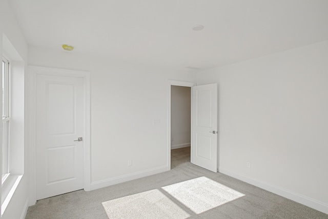 empty room featuring baseboards and light colored carpet