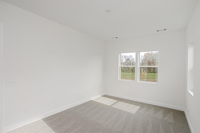 carpeted empty room featuring visible vents and baseboards