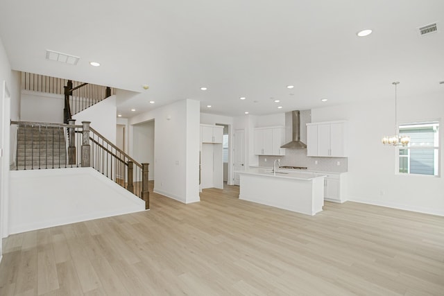 unfurnished living room with visible vents, a sink, and light wood-style floors