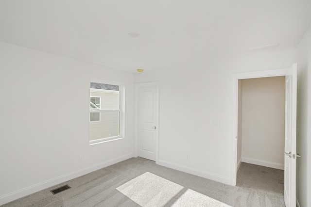 empty room featuring baseboards, light carpet, and visible vents