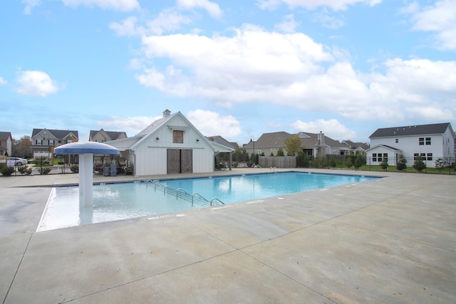community pool with fence, a patio area, and a residential view