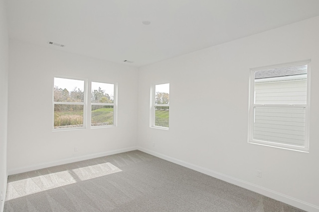 empty room with carpet floors, baseboards, and visible vents