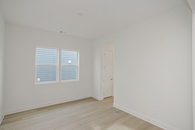 spare room featuring baseboards, visible vents, and light wood-style flooring