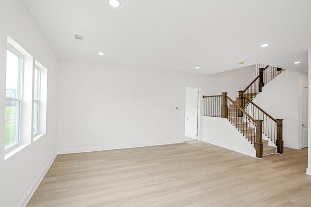 unfurnished room with recessed lighting, plenty of natural light, light wood finished floors, and stairs