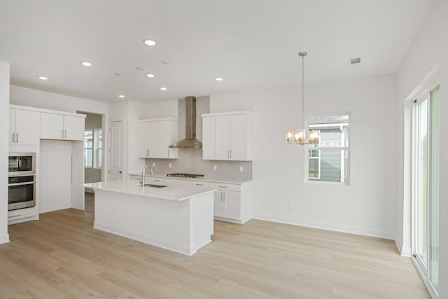 kitchen with stainless steel oven, built in microwave, wall chimney exhaust hood, a wealth of natural light, and backsplash