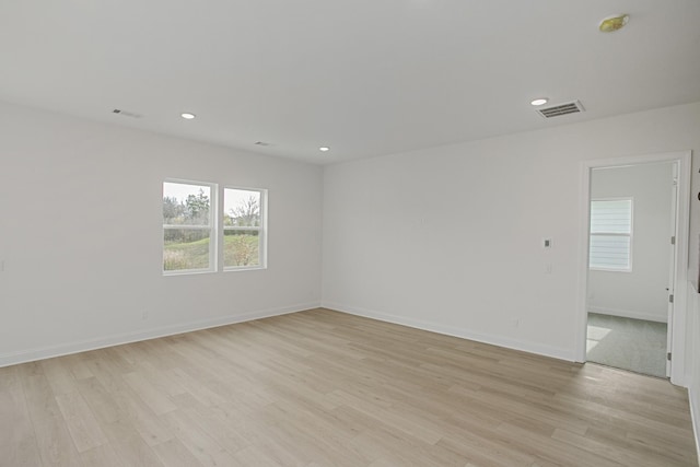 unfurnished room with a wealth of natural light, light wood finished floors, and visible vents
