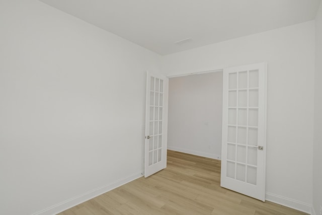 spare room featuring french doors, baseboards, visible vents, and light wood-type flooring