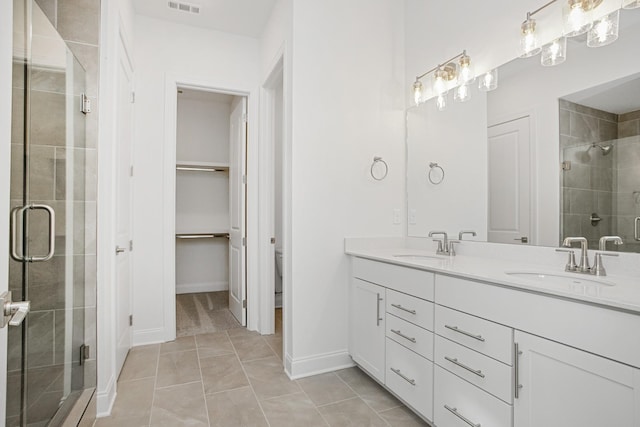 full bathroom with double vanity, a sink, a spacious closet, and a shower stall