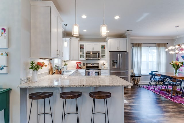 kitchen with appliances with stainless steel finishes, a peninsula, visible vents, ornamental molding, and glass insert cabinets