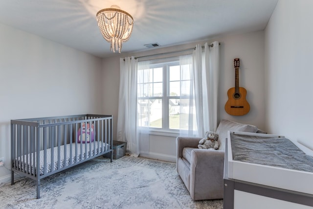 bedroom with visible vents, baseboards, a crib, and an inviting chandelier