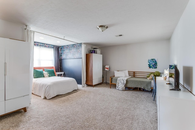 bedroom featuring visible vents, a textured ceiling, and light carpet