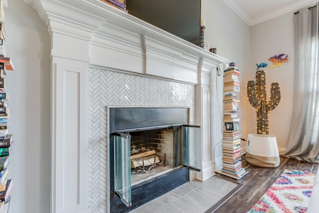 details featuring crown molding, wood finished floors, and a tile fireplace