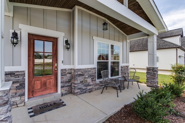 view of exterior entry with a porch, board and batten siding, and stone siding