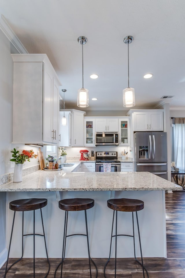 kitchen with crown molding, white cabinets, stainless steel appliances, and a peninsula