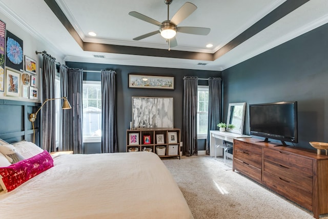 bedroom with crown molding, a tray ceiling, multiple windows, and carpet