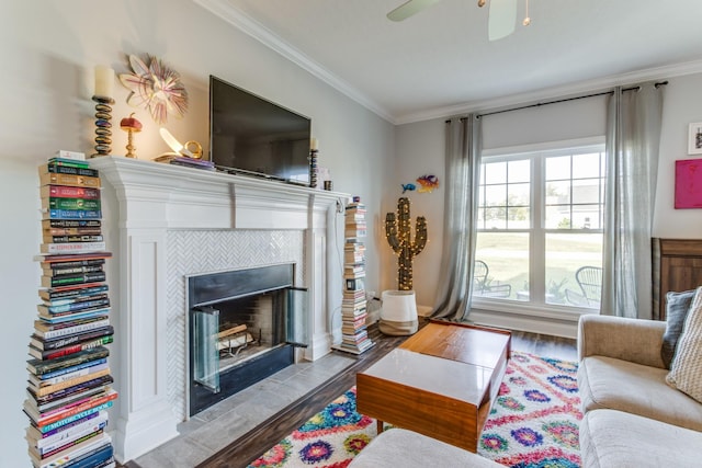 living room featuring a ceiling fan, ornamental molding, wood finished floors, and a tiled fireplace