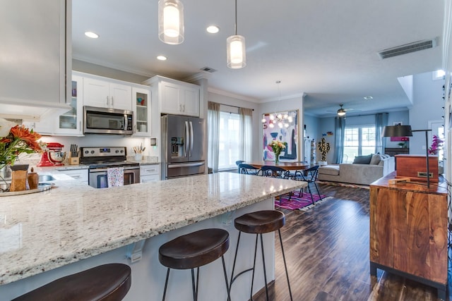 kitchen featuring crown molding, a peninsula, appliances with stainless steel finishes, and visible vents