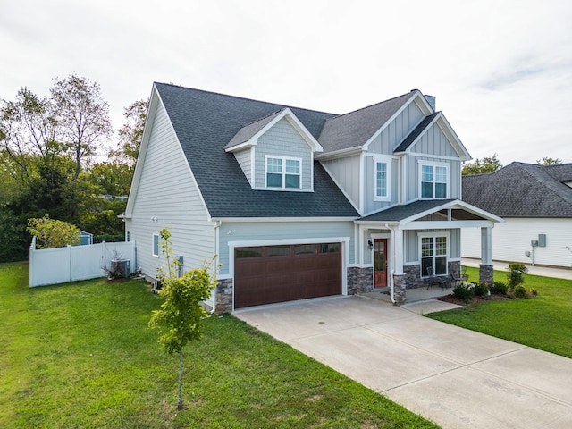 craftsman-style house with board and batten siding, fence, driveway, and a front lawn