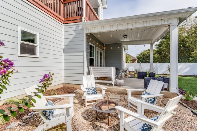 view of patio / terrace with fence, a fire pit, and a balcony
