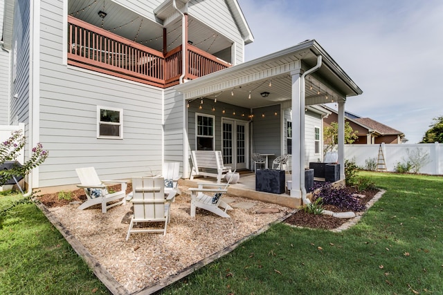 rear view of house with a patio, a balcony, fence, and a yard