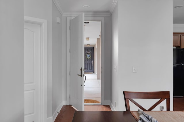 hall featuring baseboards, ornamental molding, and light wood-style flooring