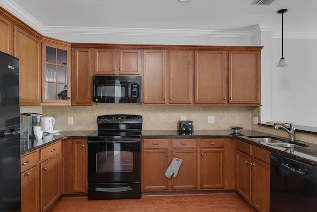 kitchen featuring brown cabinets, dark stone counters, a sink, and black appliances