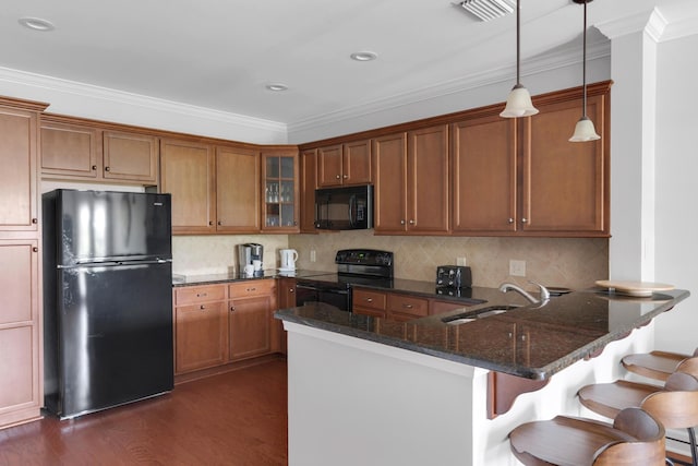 kitchen featuring visible vents, a peninsula, dark stone counters, a sink, and black appliances