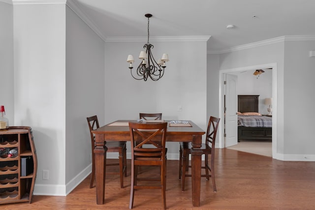dining area featuring crown molding, baseboards, wood finished floors, and a notable chandelier