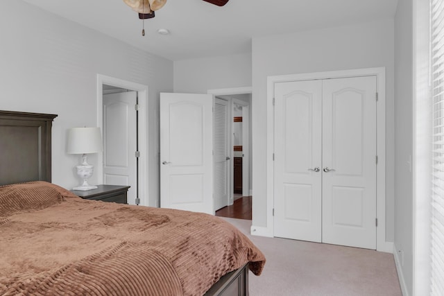 bedroom with a ceiling fan, baseboards, light carpet, and a closet