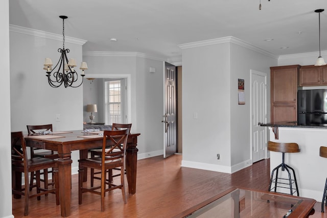 dining area with baseboards, a chandelier, ornamental molding, and wood finished floors