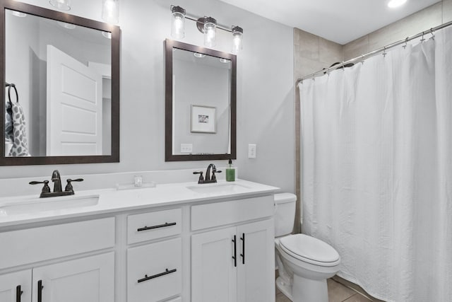 bathroom with double vanity, a sink, tile patterned floors, and toilet