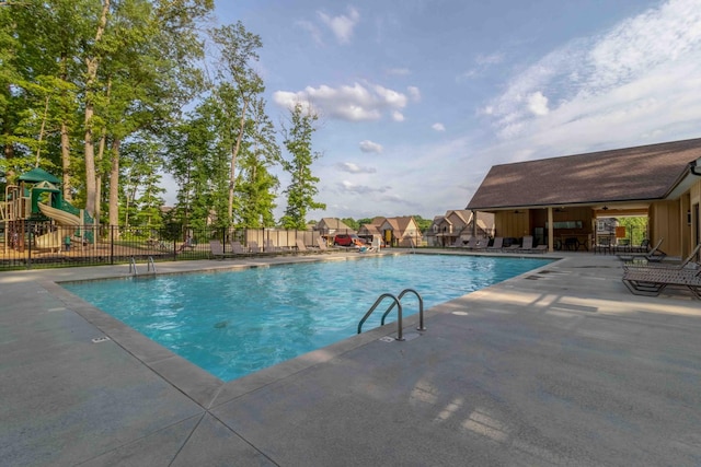 pool with a patio, fence, and playground community