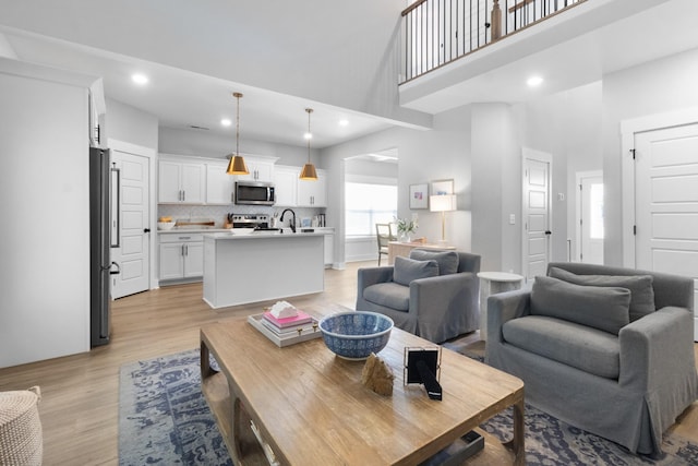 living room with light wood-style floors, recessed lighting, and a towering ceiling