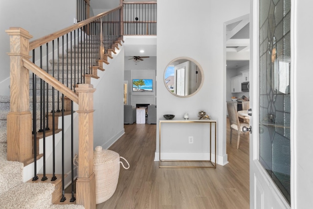 entrance foyer with baseboards, ceiling fan, wood finished floors, and stairway