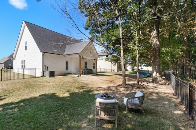 rear view of house featuring a fenced backyard, roof with shingles, central air condition unit, and a yard
