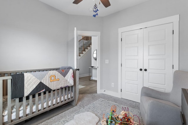 bedroom with a crib, baseboards, a closet, and ceiling fan
