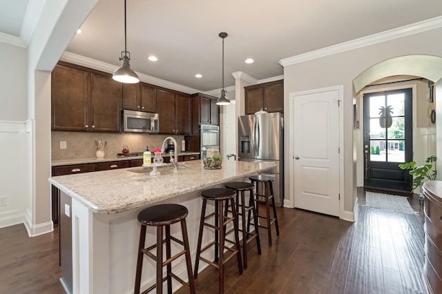 6006 Trotwood Ln, Spring Hill, TN 37174 - kitchen with dark brown cabinetry, a breakfast bar area, dark wood-type flooring, a sink, and appliances with stainless steel finishes