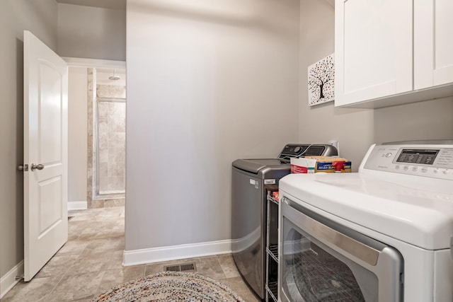 6006 Trotwood Ln, Spring Hill, TN 37174 - laundry room with washing machine and clothes dryer, cabinet space, baseboards, stone finish flooring, and visible vents