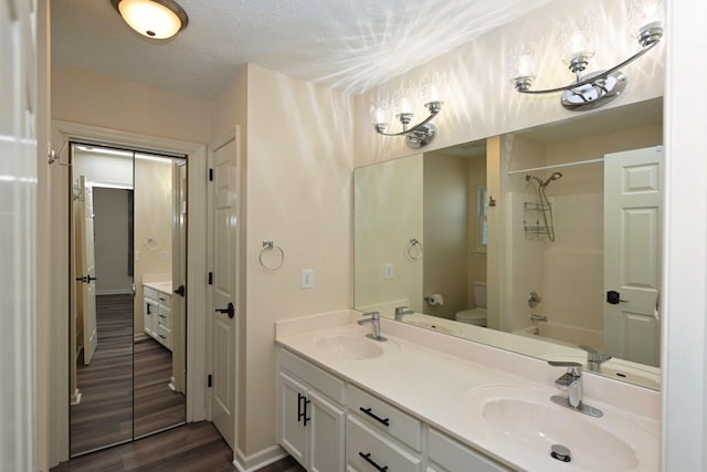 bathroom featuring double vanity, a sink, wood finished floors, and toilet