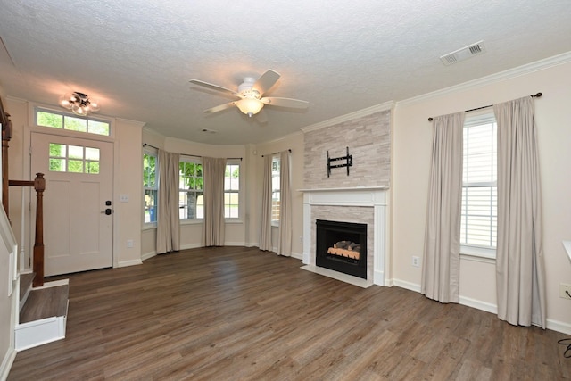 unfurnished living room with visible vents, a textured ceiling, wood finished floors, and a wealth of natural light
