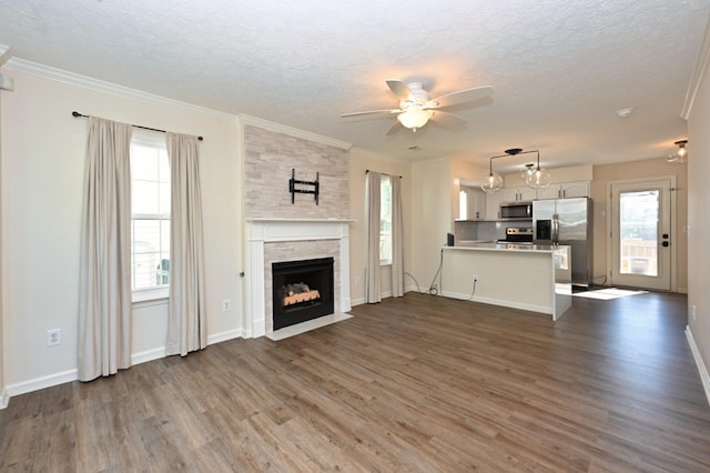 unfurnished living room featuring a healthy amount of sunlight, ceiling fan, dark wood-style floors, and a textured ceiling