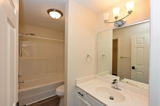 full bath featuring a textured ceiling, shower / tub combination, wood finished floors, vanity, and toilet