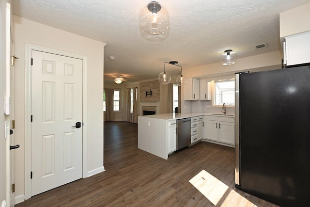 kitchen with a peninsula, a fireplace, open floor plan, white cabinetry, and appliances with stainless steel finishes