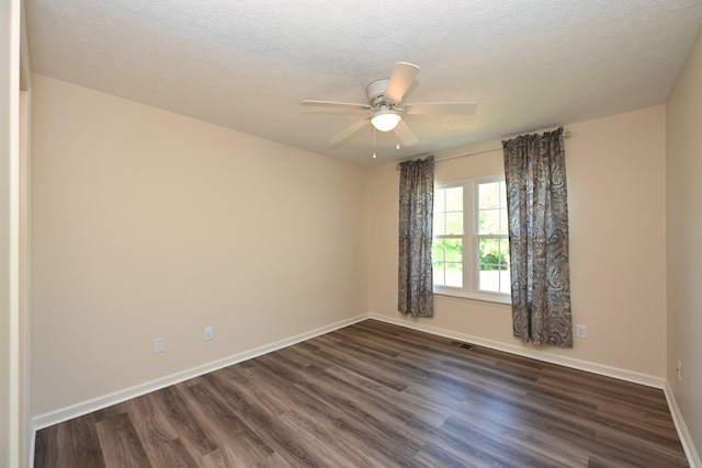 spare room featuring baseboards, a ceiling fan, dark wood finished floors, and a textured ceiling