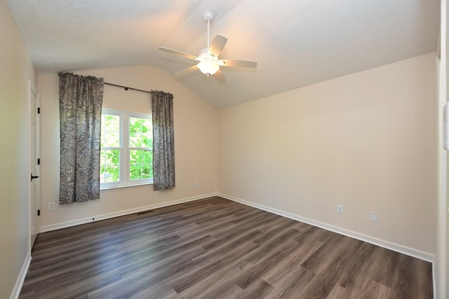 empty room featuring baseboards, a ceiling fan, dark wood finished floors, and vaulted ceiling